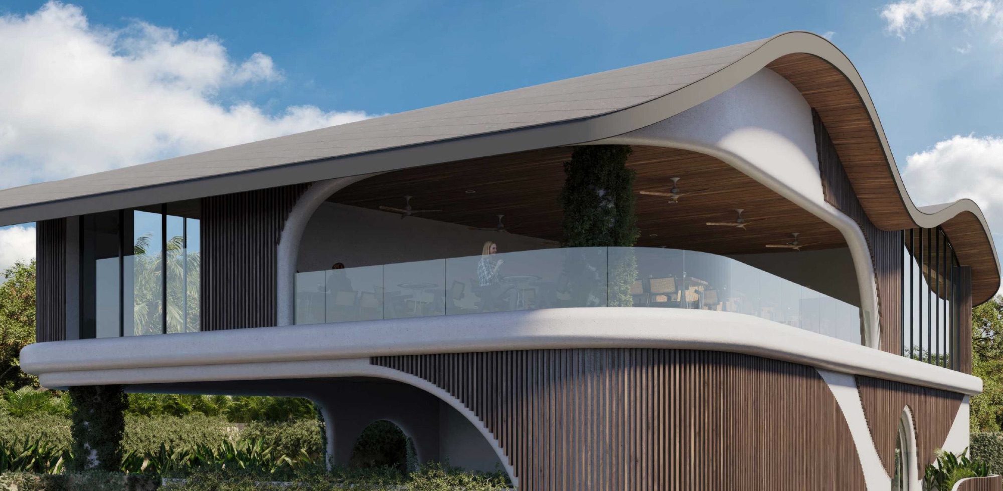 The resort's flowing organic roofline and curved balconies wrapping into the Uluwatu jungle canopy under a bright sky