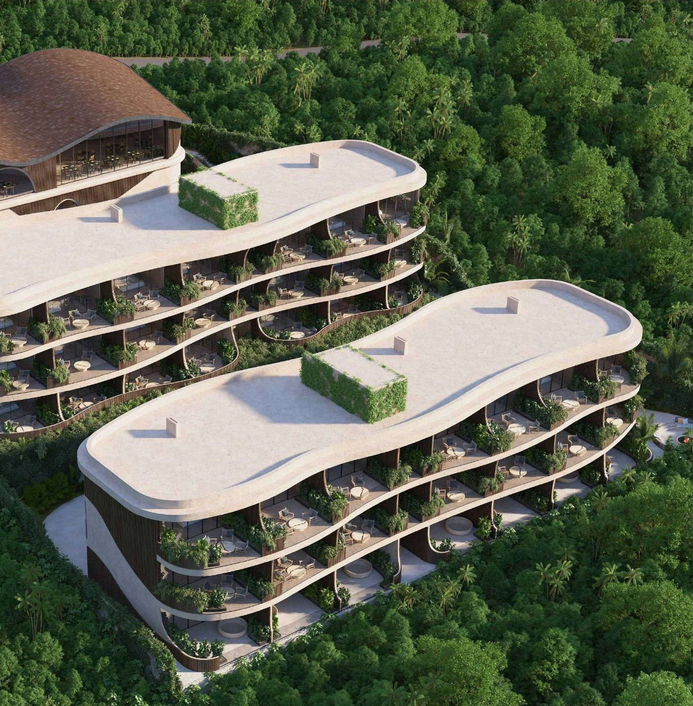Aerial view of Luma — two residence buildings with wavy roofs and cascading planted terraces, set into dense Uluwatu jungle