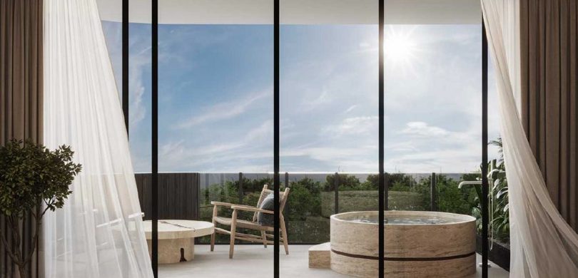 Premium residence terrace with a round travertine jacuzzi and ocean view behind sheer curtains